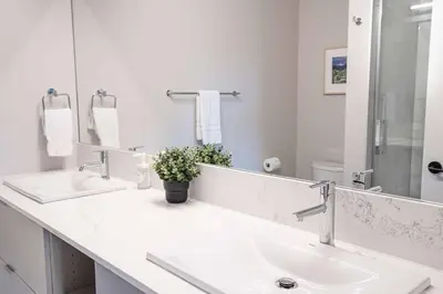 a white bathroom with two sinks and a mirror at Northern Exposure by Revelstoke Vacations in Revelstoke