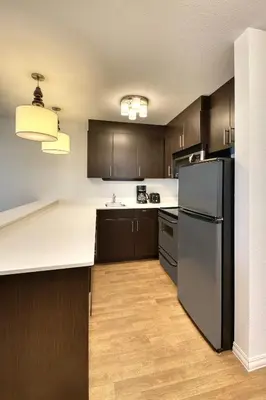 a kitchen with a black refrigerator and wooden cabinets at TownePlace Suites by Marriott Red Deer in Red Deer