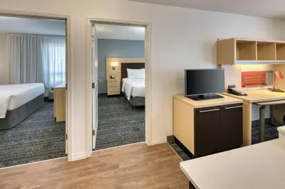 a hotel room with a bed and a desk with a television at TownePlace Suites by Marriott Red Deer in Red Deer