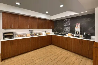 a kitchen with wooden cabinets and a chalkboard on the wall at TownePlace Suites by Marriott Red Deer in Red Deer
