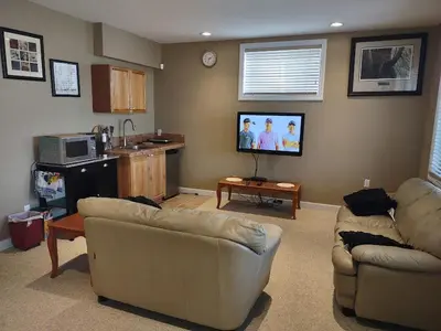 a living room with two couches and a flat screen tv at Spacious One Bedroom Walkout Basement Suite in Calgary