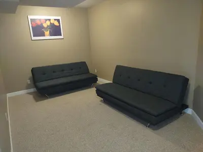 two black couches sitting in a room with a couch at Spacious One Bedroom Walkout Basement Suite in Calgary