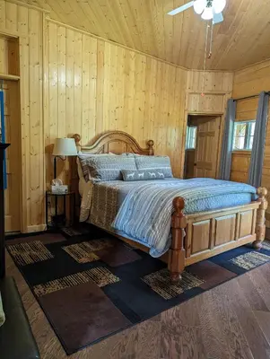 a bedroom with a bed in a room with wooden walls at Sundance Country Lodge B&B in Marlboro