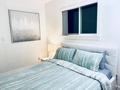a bedroom with a bed with blue sheets and a window at Charming 1BR near Metrotown DT Burnaby/ Vancouver in Vancouver