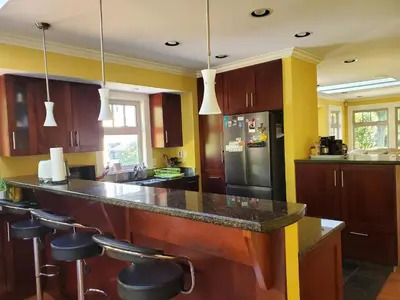 a kitchen with a counter with stools and a refrigerator at Elegant, Sunny Modern Home with Skylights - Kitsilano, Vancouver in Vancouver