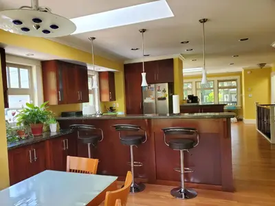 a kitchen with wooden cabinets and a table with chairs at Elegant, Sunny Modern Home with Skylights - Kitsilano, Vancouver in Vancouver