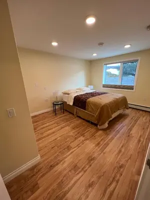 a bedroom with a bed and a wooden floor at Bluejay Suites B&B in Whitehorse