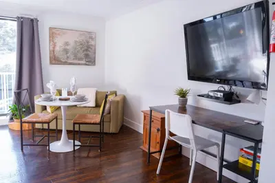 a living room with a dining room table and a tv at Wanderlust Studio Suite with Private Patio in Harrison Hot Springs