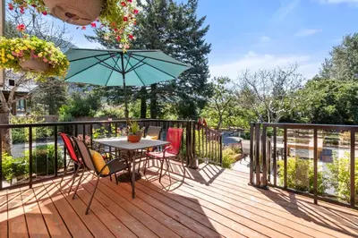 a deck with a table and chairs and an umbrella at Lake Time Harrison in Harrison Hot Springs