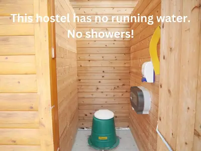a bathroom with a toilet in a wooden wall at HI Rampart Creek - Hostel in Saskatchewan River Crossing
