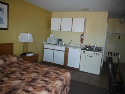 a room with a kitchen with a bed and a microwave at Tumbler Ridge Inn in Tumbler Ridge