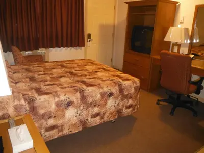 a hotel room with a bed and a desk and a television at Tumbler Ridge Inn in Tumbler Ridge