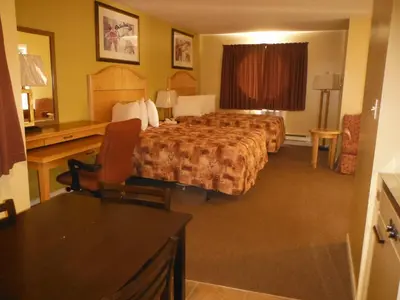 a hotel room with two beds and a desk at Tumbler Ridge Inn in Tumbler Ridge