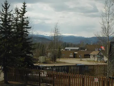 a fence with a tree and mountains in the background at Tumbler Ridge Inn in Tumbler Ridge
