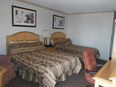 a hotel room with two beds and a chair at Tumbler Ridge Inn in Tumbler Ridge