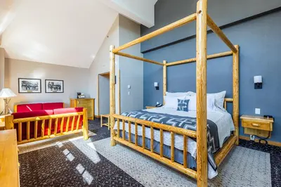 a bedroom with a wooden bed and a red couch at Brewster Mountain Lodge in Banff