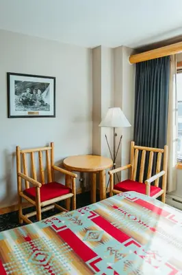 a bedroom with a bed and two chairs and a table at Brewster Mountain Lodge in Banff