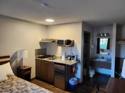 a small kitchen with a sink and a microwave at Bon Voyage Inn in Prince George