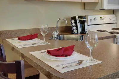 a kitchen with two plates and wine glasses on a counter at Coast Grimshaw Hotel & Suites in Grimshaw