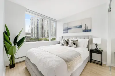 a white bedroom with a large bed and a window at Heart of Downtown 1 bd Entire Condo - Pool, Gym, Parking, Office, AC in Vancouver