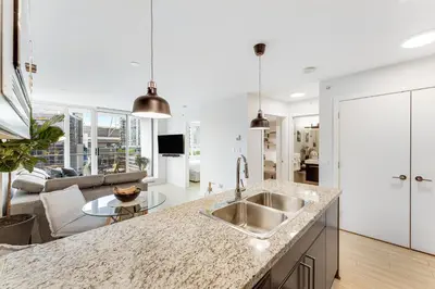 a kitchen with a sink and a living room at Heart of Downtown 1 bd Entire Condo - Pool, Gym, Parking, Office, AC in Vancouver
