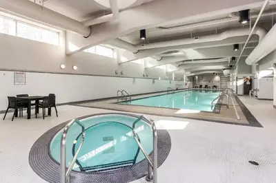 a large swimming pool in a building with a table at Heart of Downtown 1 bd Entire Condo - Pool, Gym, Parking, Office, AC in Vancouver
