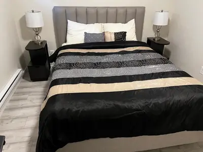 a bedroom with a large bed with two lamps at The Waterfront cozy 1 bd suite in Rockland Park, Tuscany NW in Calgary