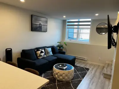 a living room with a blue couch and a table at The Waterfront cozy 1 bd suite in Rockland Park, Tuscany NW in Calgary