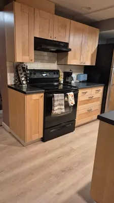 a kitchen with a black stove and wooden cabinets at Garden suite on Trinity St in Vancouver