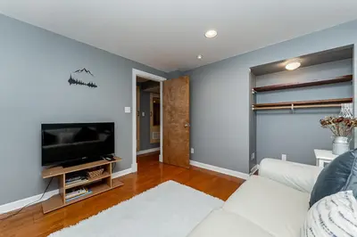a living room with a white couch and a tv at Garden suite on Trinity St in Vancouver