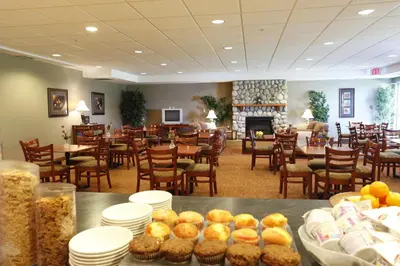 a restaurant with tables and chairs and a fireplace at Pomeroy Inn and Suites Dawson Creek in Dawson Creek