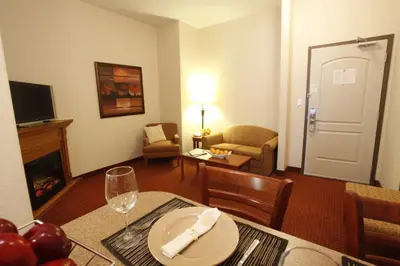 a living room with a dining table and a living room with a living room at Pomeroy Inn and Suites Dawson Creek in Dawson Creek