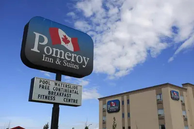 a sign for a monopoly inn and suites in front of a building at Pomeroy Inn and Suites Dawson Creek in Dawson Creek