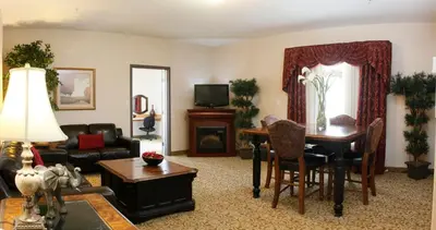 a living room with a table and a piano at Pomeroy Inn and Suites Dawson Creek in Dawson Creek