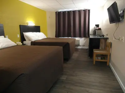a hotel room with two beds and a desk and a television at West View Motel in Hanna