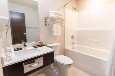 a white bathroom with a toilet and a sink at The Kanata by BCMInns Blairmore in Blairmore