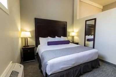 a hotel room with a large bed and two lamps at The Kanata by BCMInns Blairmore in Blairmore