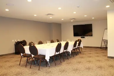 a conference room with a table and chairs and a screen at The Kanata by BCMInns Blairmore in Blairmore