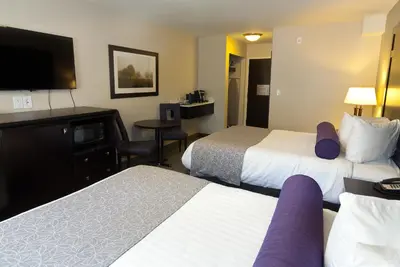a hotel room with two beds and a flat screen tv at The Kanata by BCMInns Blairmore in Blairmore