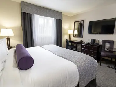 a hotel room with a large bed and a desk at The Kanata by BCMInns Blairmore in Blairmore