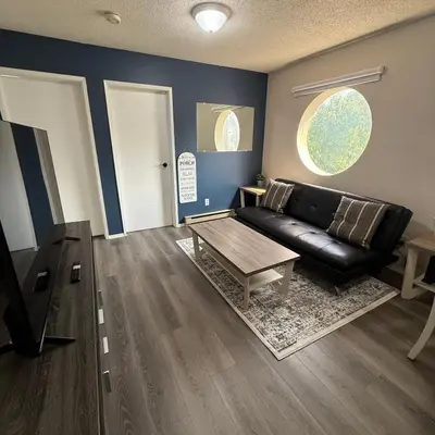 a living room with a black leather couch and a table at Cozy Beach 2 bedroom apartment in Invermere