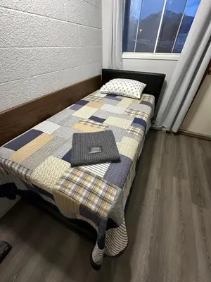 a bed with a pillow on top of it next to a window at Cozy Beach 2 bedroom apartment in Invermere