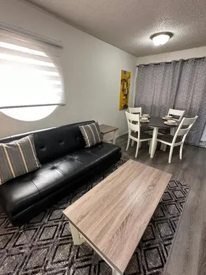 a living room with a black leather couch and a table at Cozy Beach 2 bedroom apartment in Invermere
