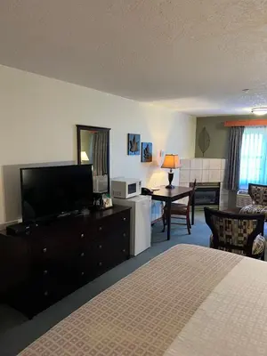 a bedroom with a bed and a television and a table at The Grand Hotel Nanaimo in Nanaimo