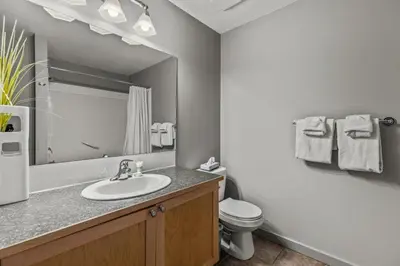 a bathroom with a sink and a toilet and a mirror at Rocky Mountain Getaway with Outdoor Heated Pool, 3 Hot Tubs, Gym, BBQ, Garage & 24 hour Reception near Banff in Canmore