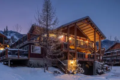 a large log cabin in the snow at night at Lush Mountain Accommodations in Golden