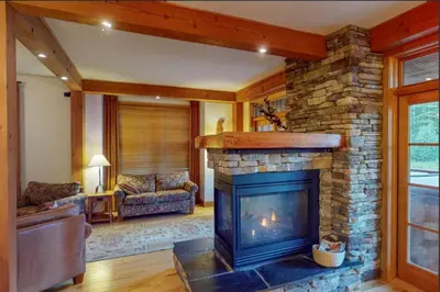 a living room with a stone fireplace in a house at Lush Mountain Accommodations in Golden