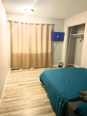 a bedroom with a bed and a television in a room at Flowealth Suites - Private Rooms Near West Edmonton Mall in Edmonton
