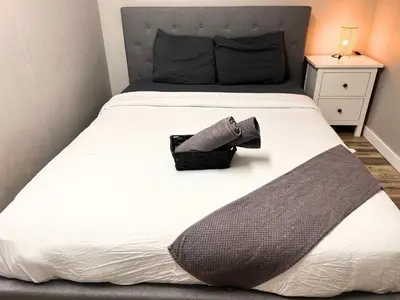 a bed with a pair of shoes sitting on it at Flowealth Suites - Private Rooms Near West Edmonton Mall in Edmonton