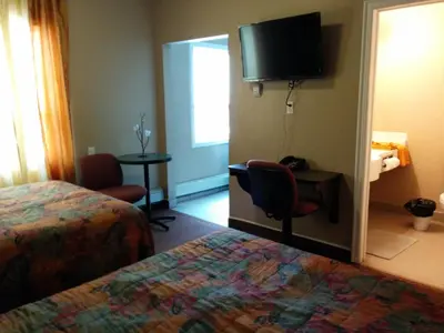 a hotel room with a bed and a flat screen tv at Bonnyville Hotel in Bonnyville